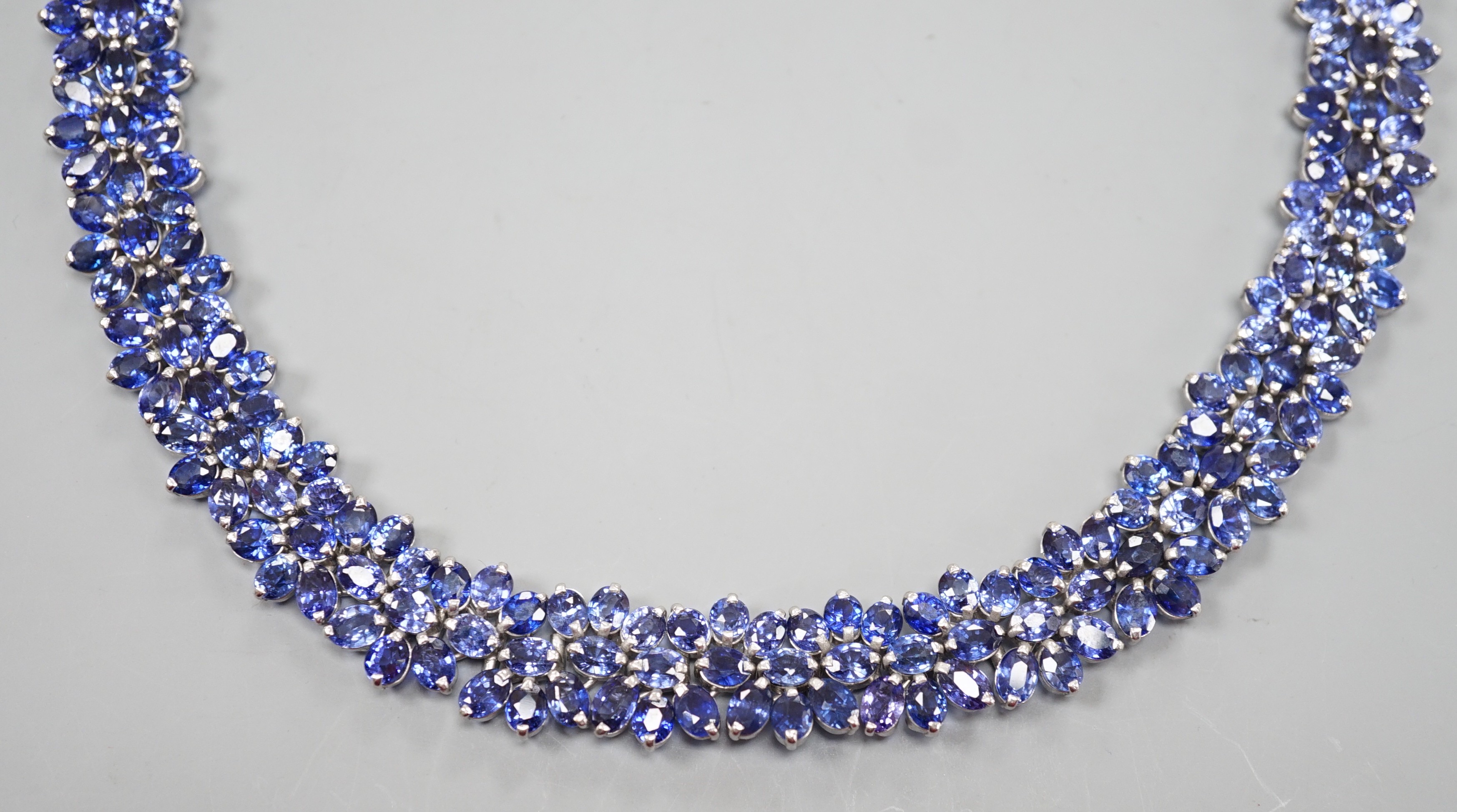 A continental base metal and synthetic sapphire? flower head cluster set necklace, approximately 39cm.